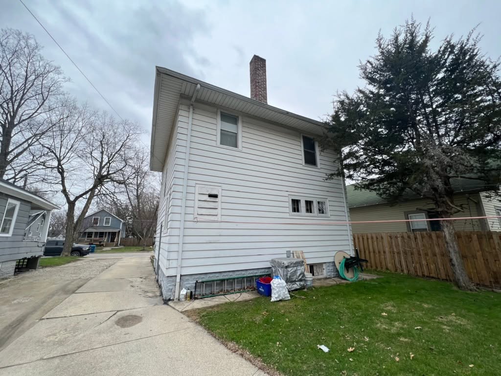 Two-story home with old white siding before replacement